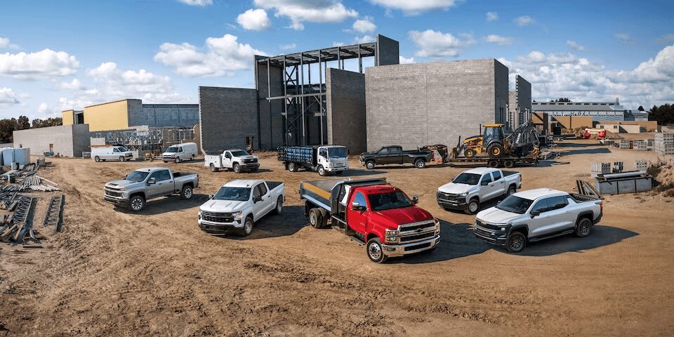 A group of trucks parked in the dirt.