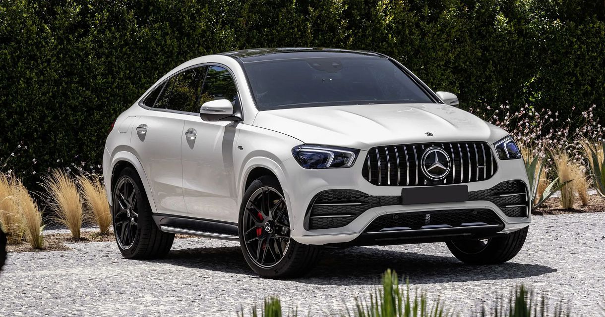 A white mercedes gle coupe parked on top of gravel.