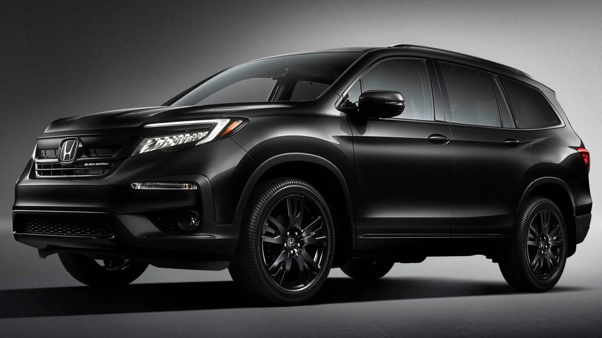 A black honda suv is parked in the dark.